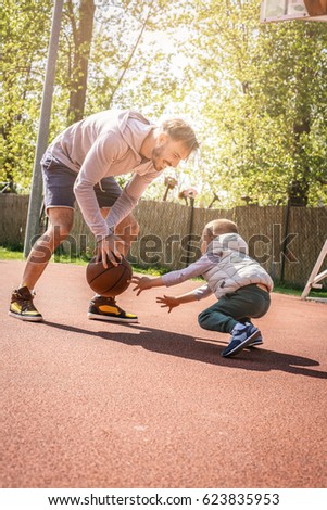 Dad and his son playing basketball together. Enjoying in spring day.