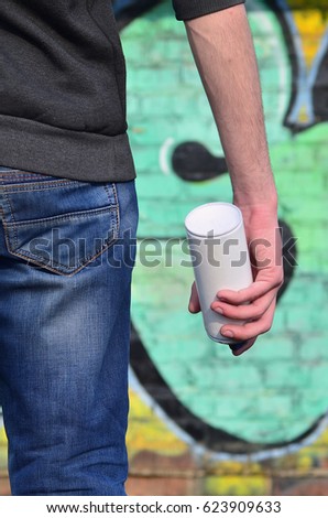 A photo of a street artist who draws a new colored picture on a brick wall. One of the types of street art is the youth graffiti culture. Decoration of walls of old and abandoned buildings