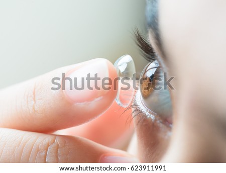 Young woman putting contact lens in her right eye, selective focus on cornea of  the eye. Royalty-Free Stock Photo #623911991