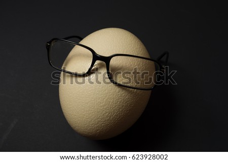 Ostrich egg with glasses at black background
