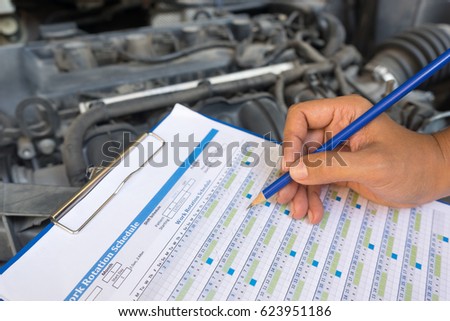 Close-up of Mechanic man holding clipboard and check the car. Check by period and lifetime for safety. Royalty-Free Stock Photo #623951186