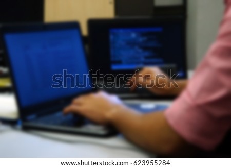 Defocus or blur image of young programmer working on computer.