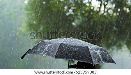 A person holding an umbrella under heavy rain.