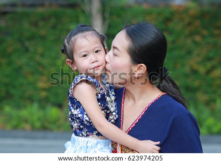 Portrait of mother and daughter in traditional songkran festival dress kissing.