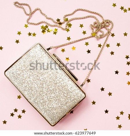 Festive evening golden clutch with star sprinkles on pink. Holiday and celebration background. Luxury accessories and party concept. Square