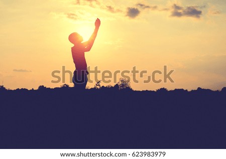 Silhouette of man pray with sunset background