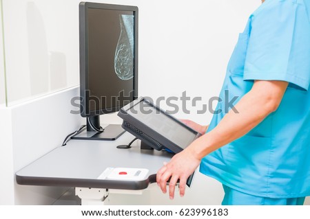 Doctor looking at mammogram snapshot of breasts of a female patient on the monitor. Selective focus
