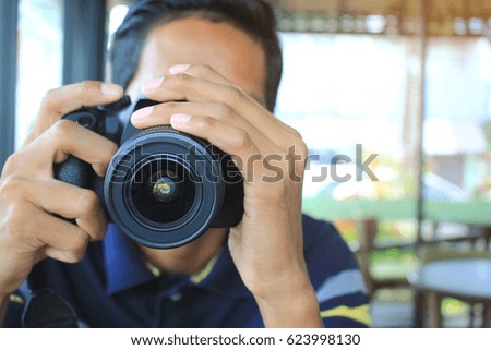 Young man photographer looking at camera screen in coffee shop, Concept of occupation and lifestyle