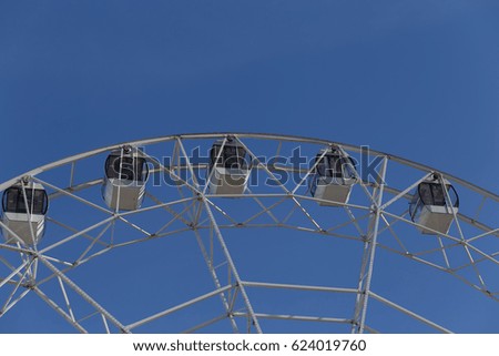 Ferris wheel makes a turn, photo on a blue sky background in a summer sunny day