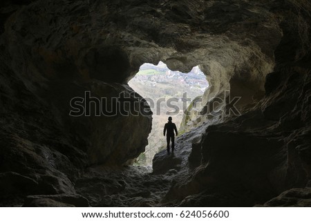  Hiker explore a beautiful cave and watch out of the tunnel. Royalty-Free Stock Photo #624056600