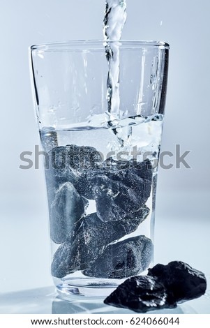 Shungite stones, a rock with an extremely high carbon content from Karelia, Russia, being used to purify water in a concept pf alternative medicine and healing