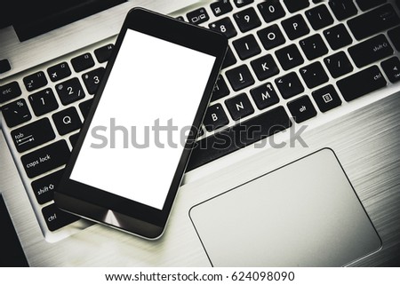 smartphone with blank screen on laptop on black modern desk