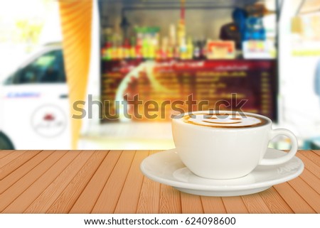 Hot smile coffee on brown wood with blur of coffee house on wheels van background.