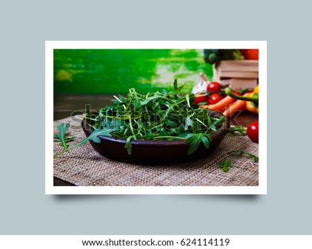 Arugula leaves in bowl. Fresh salad. Carrot and cherry tomatoes. Natural raw vegetables. Organic bio food on rustic wooden table. Photo frame design with shadow.