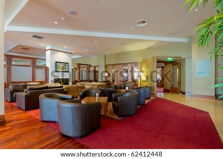 hall with leather arm-chairs and red carpet in modern Hotel interior