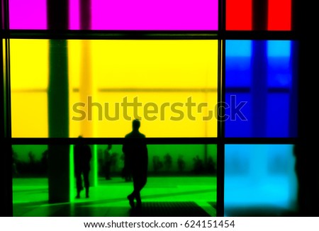 People silhouettes at modern office hall building with colorful windows.