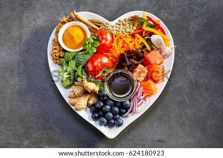 Healthy diet for the cardiovascular system with a heart-shaped plate of acai, lentils, soy sauce, ginger, salmon, carrot, tomato, turmeric, cinnamon, walnuts, garlic, peppers, broccoli, basil, onion Royalty-Free Stock Photo #624180923