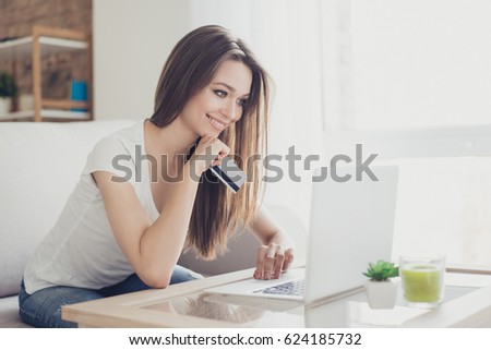 Shopper girl is buying online with a laptop and credit card sitting in nice light room