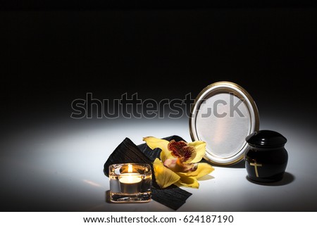 black urn with black tape,yellow orchid for sympathy card on background