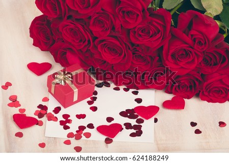 Small Valentine gift with bouquet of fresh red roses and small red hearts. Love concept