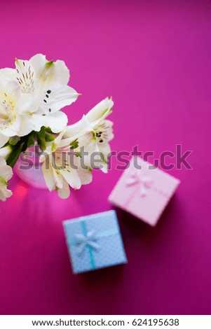 Beautiful tender bouquet of white Alstroemeria with two gift boxes on crimson background. Spring composition. Springtime. Mother`s day card.