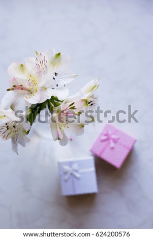 Beautiful tender bouquet of white Alstroemeria with two gift boxes on marble table. Spring composition. Springtime. Mother`s day card.