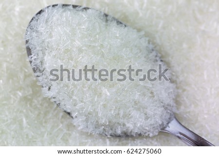 Closeup macro texture of spoon full of MSG flakes, Monosodium glutamate, sodium salt used as flavor enhancer
