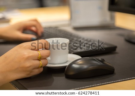 Woman hand holdding coffee cup with working table background