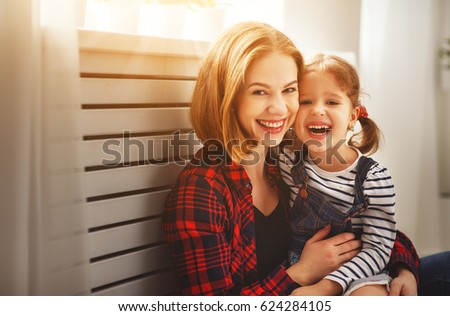 Happy family mother and child daughter laugh play and cuddle
