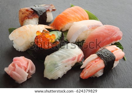 A dish of assorted sushi: Japanese amber jack, tuna,  sea bream, salmon roe, salmon, shrimp, eel, crab (8 kinds) and red pickled ginger/ Mixed Sushi Platter on black stone plate, Japanese Food Royalty-Free Stock Photo #624379829