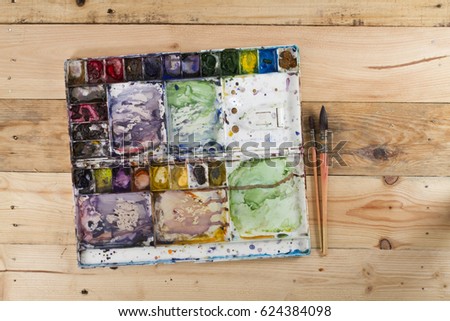 paintbrush, color palette on wood background