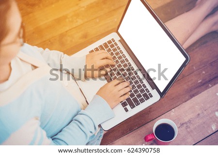 Beautiful girl used Laptop with bank screen and coffee cup sitting on a wooden floor, vintage tone.