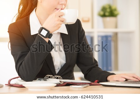 portrait beautiful girl drinking coffee using mug working on the mobile computer and her smart watch have message showing blank screen on the photo with sunlight closeup.