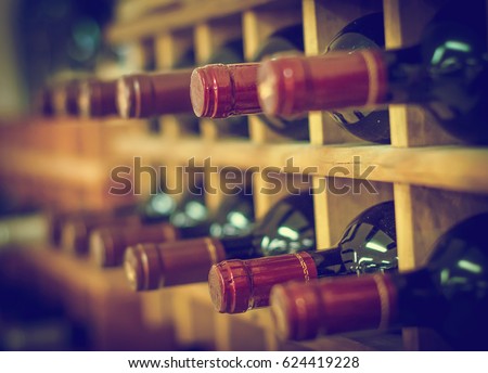 Red wine bottles stacked on wooden racks Royalty-Free Stock Photo #624419228