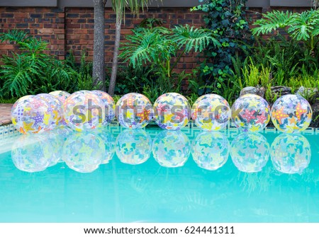 Beach balls floating on water in home swimming pool party decor