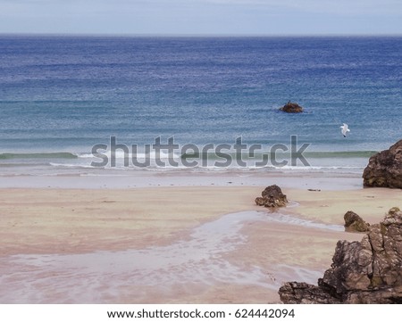 Sand beach and blue ocean in Scotland with waves.