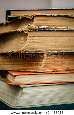 A stack of old worn books on a background of dark fabric