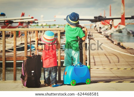 little boy and girl looking at seaplanes in Maldives Royalty-Free Stock Photo #624468581