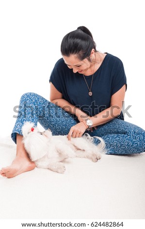 Cute picture of young female relaxing and playing with her bichon on white background