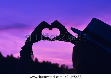 Silhouette hand in the heart shape at the sky sunset background.love concept 