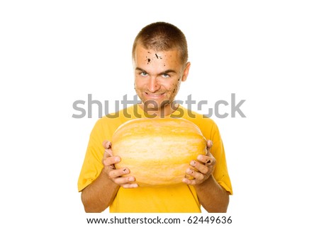 Handsome young man holding a big yellow pumpkins in their hands. An evil smile. Lots of copyspace and room for text on this isolate
