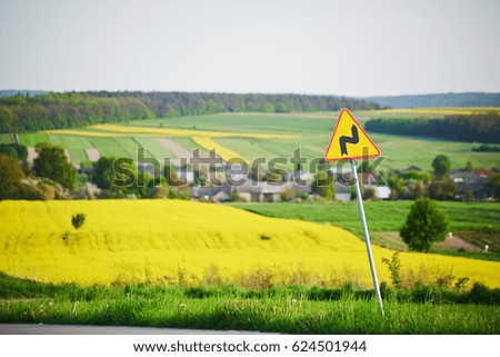 Road sign with pedestrian attention and behind sign of canola field
