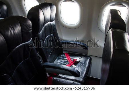 Seat belt on seat shot in airplane with Black seat.