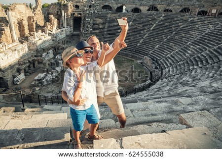 Young positive family take a self photo on the antique amphitheater in Side, Turkey