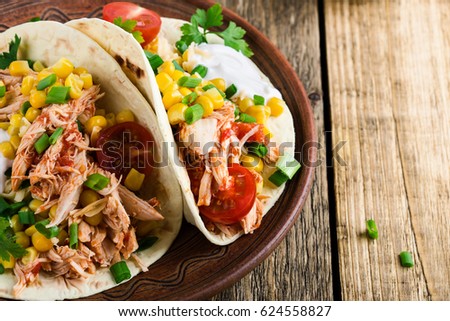 Homemade slow cooker chicken taco with corn served on rustic ceramic plate on wooden table, mexican style