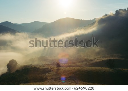 Landscape of the morning misty mountains. The magic place of the earth. Altai. Glare of the sun.