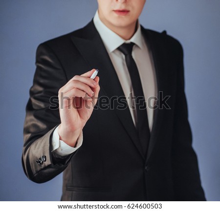 businessman in black suit writing something on glass board with marker