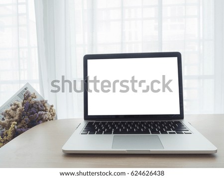 wood office table with blank screen on laptop and bunch of flower on blurry beautiful white drape window texture background.