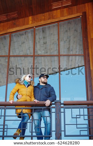 Photo of a young cheerful couple in love walking in the mountains and looking to the side, holding hands