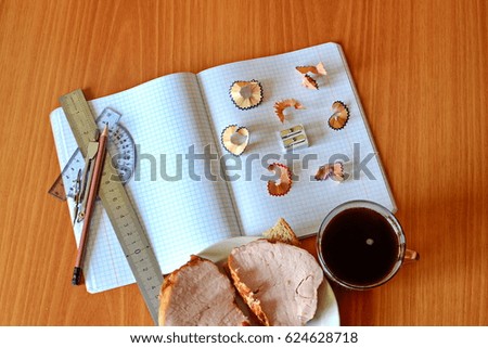 cell school notebook, pencil, sharpener, ruler, protractor, compass and sawdust with cup of coffee and big sandwich on wood table
